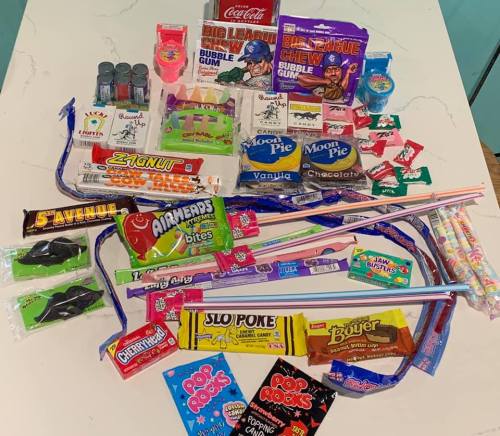 A colorful assortment of candies and snacks, including gum, chocolate bars, and novelty treats, arranged on a table.