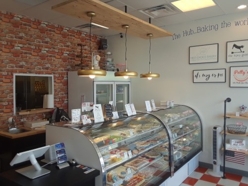 A cozy bakery interior featuring a glass display case, brick walls, and warm lighting.