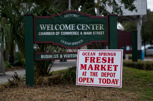 Sign for Ocean Springs Fresh Market at the Depot, with a Welcome Center sign in the background. Open today.