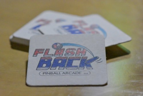 Coasters featuring the logo of "Flashback Pinball Arcade" on a wooden surface.