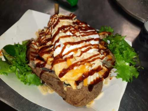 A delicious dish featuring a brown bread base topped with lettuce, sauce, and a mix of creamy and crunchy toppings.