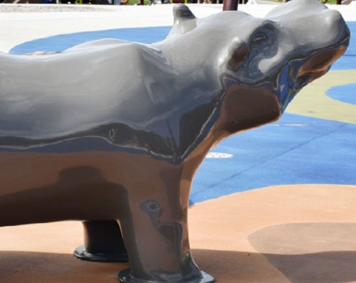 A shiny gray hippo sculpture on a colorful playground surface.