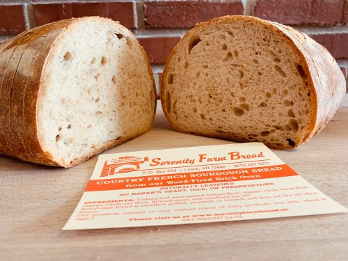 A loaf of country French sourdough bread, sliced in half, with a card detailing its ingredients and origin.