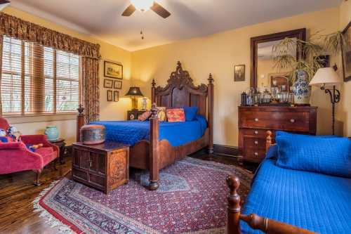 Cozy bedroom featuring a wooden bed, blue bedding, vintage decor, and a warm color palette with a patterned rug.
