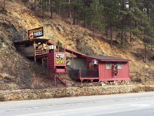 A red building with a sign for "Underground Tours" near a hillside, surrounded by trees.
