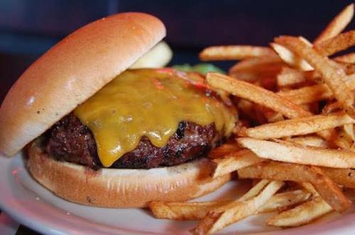 A juicy cheeseburger with melted cheddar cheese, served with a side of crispy French fries.