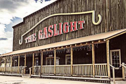 A rustic wooden building with a sign reading "The Gaslight" and a porch, set against a cloudy sky.