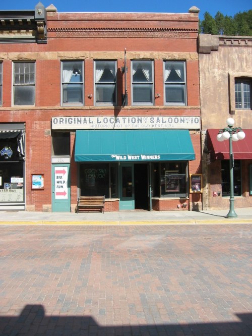 Historic building with green awning reading "Original Location of Saloon #10," located in a brick street setting.