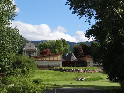 A scenic view of a green landscape featuring modern buildings and trees, with mountains in the background under a blue sky.