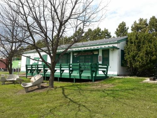 A green and white building with a porch, surrounded by trees and grass, identified as a museum.