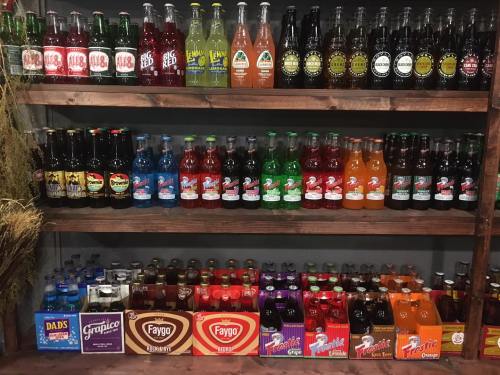 A wooden shelf displaying a variety of colorful soda bottles in different flavors and brands.