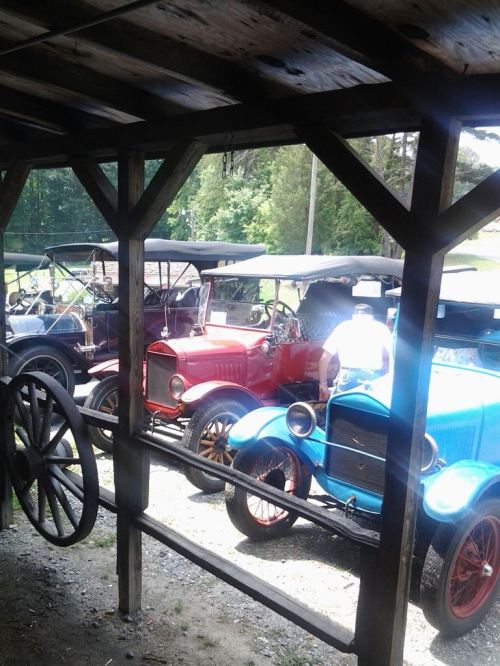 A collection of vintage cars, including red and blue models, viewed from a wooden structure.