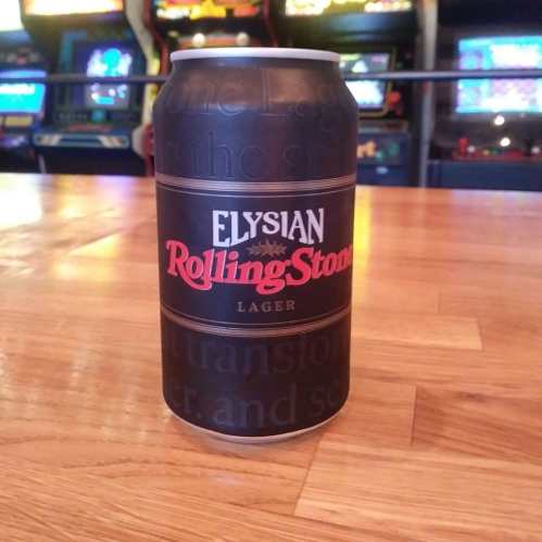 A can of Elysian Rolling Stone Lager on a wooden table, with arcade games visible in the background.