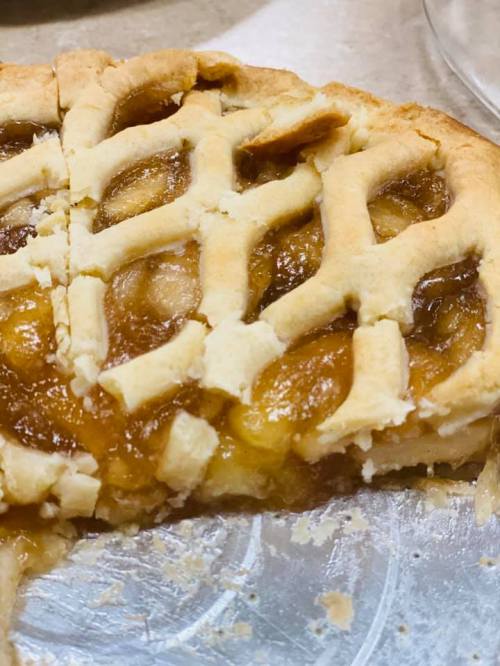 A freshly baked pie with a golden lattice crust and a slice removed, revealing a gooey filling.