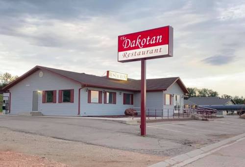 A blue building with a red sign reading "The Dakotan Restaurant" and a parking area in front.