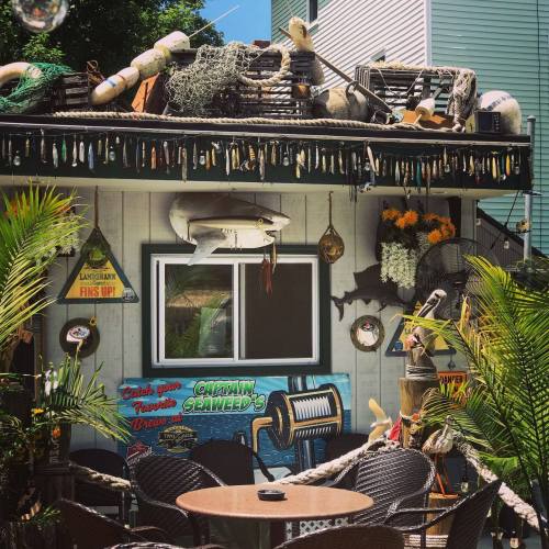 A colorful seaside-themed restaurant exterior with fishing gear, decorations, and outdoor seating.