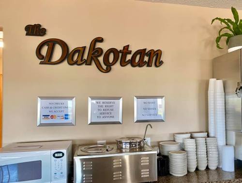 Sign for "The Dakotan" above a countertop with a microwave, dishes, and service policy notices.
