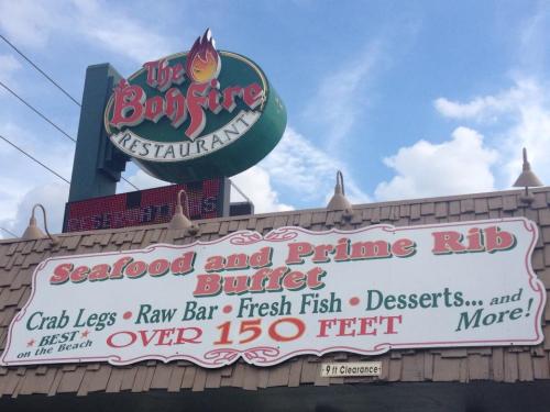 Sign for The Bonfire Restaurant featuring a seafood and prime rib buffet, highlighting crab legs, fresh fish, and desserts.