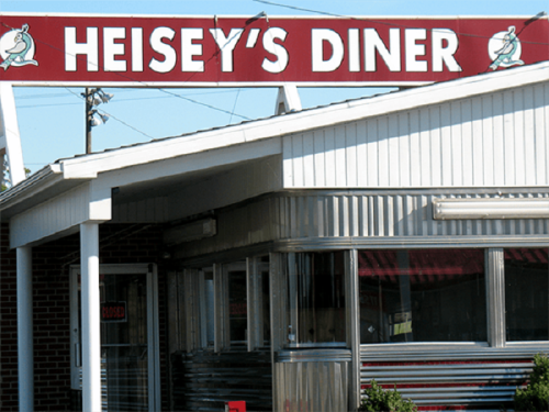 Sign for Heisey's Diner, featuring a red background with white lettering, and a classic diner exterior.