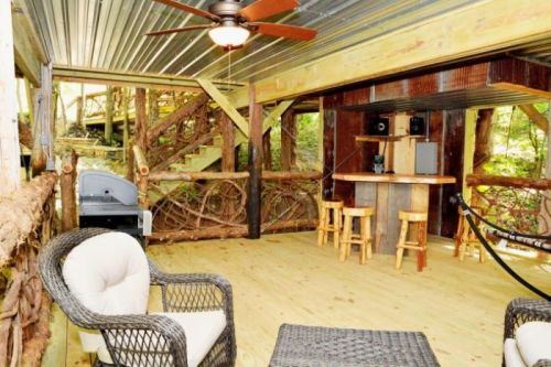 Cozy interior with wooden decor, a bar area, seating, and a staircase surrounded by nature.