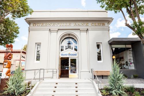 Exterior of the Guerneville Bank Club, featuring a "Grand Opening" sign and steps leading to the entrance.