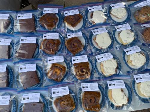 A table displaying various baked goods in plastic bags, each labeled with a description and name.