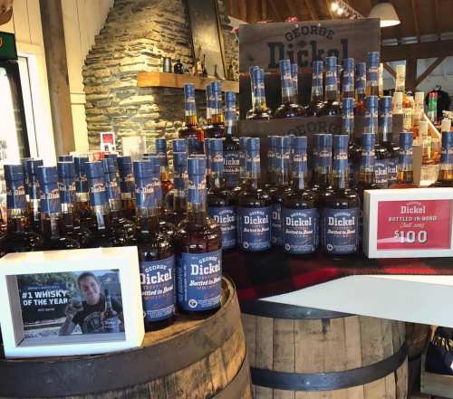 A display of George Dickel whiskey bottles stacked on barrels, with a sign highlighting its award as #1 Whisky of the Year.