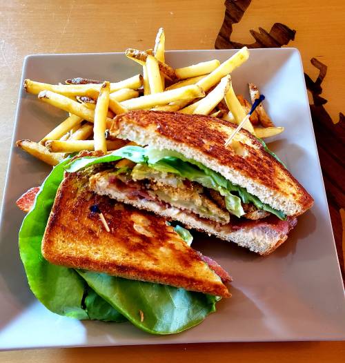 A toasted sandwich filled with lettuce and crispy ingredients, served with a side of golden French fries.