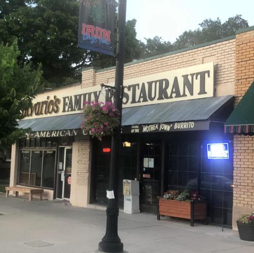 Exterior of a family restaurant with a sign reading "Estario's Family Restaurant" and a colorful hanging flower basket.