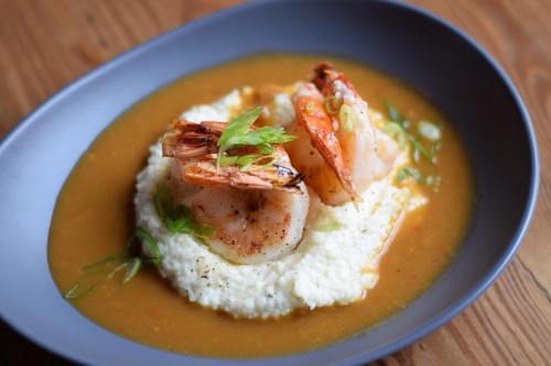 A bowl of creamy grits topped with shrimp and green onions in a flavorful broth.