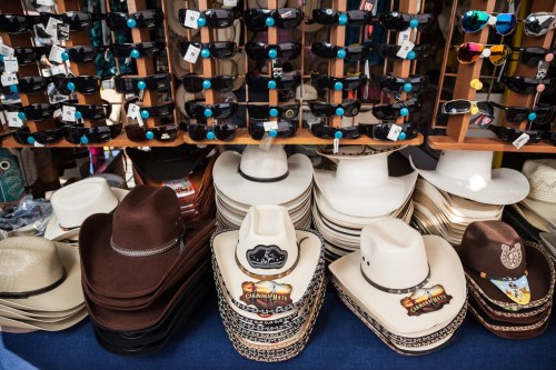 A display of various cowboy hats and sunglasses at a market stall.