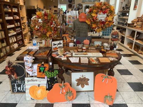 A cozy display of fall-themed decorations and crafts on a wooden table, surrounded by autumn wreaths and seasonal items.