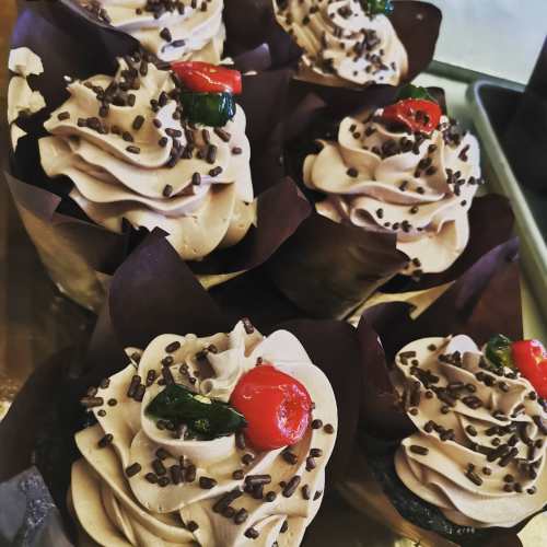 Delicious chocolate cupcakes topped with swirls of frosting, chocolate sprinkles, and cherries.