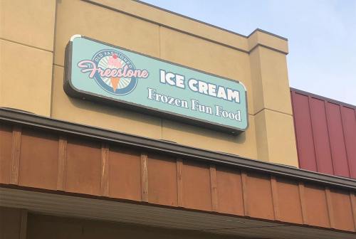 Sign for "Freestone Ice Cream" featuring the tagline "Frozen Fun Food" on a storefront.