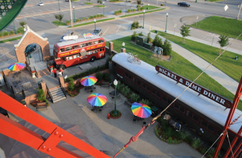 Aerial view of Nickel & Dime Diner featuring a red bus and colorful umbrellas in an outdoor seating area.