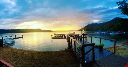 A serene lakeside view at sunset, featuring docks, boats, and a forested shoreline under a colorful sky.