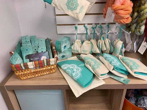 A display of teal and cream bags and boxes, featuring a mandala design, arranged on a wooden shelf.