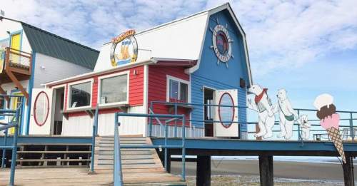 Colorful beachside building with a sign, featuring cartoon polar bears enjoying ice cream on the deck.