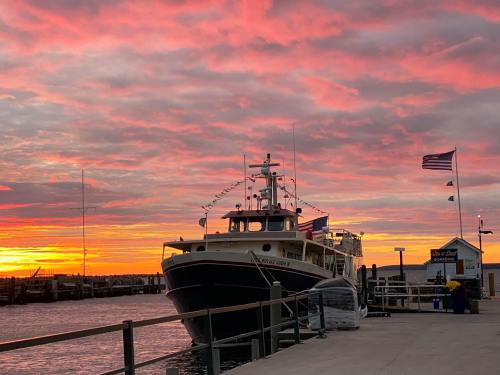 A boat docked at a pier under a vibrant sunset with colorful clouds and flags waving in the breeze.