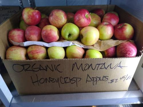 A box filled with organic Honeycrisp apples, labeled "Organic Montana Honeycrisp Apples" with a price of $2.50.