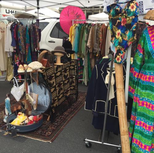 A vibrant outdoor market stall filled with colorful clothing, accessories, and unique vintage items.