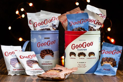 Two containers of GooGoo Clusters surrounded by assorted packs of Original, Pecan, and Peanut Butter flavors.