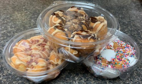 Three clear containers filled with assorted mini donuts topped with chocolate, sprinkles, and bacon bits.