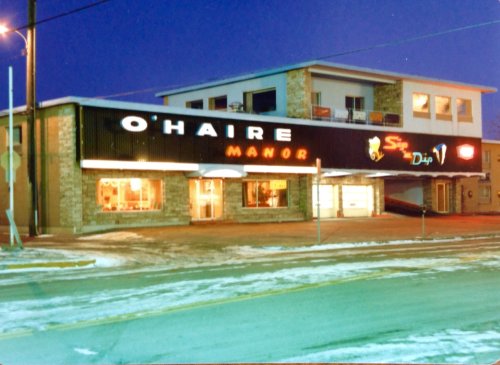O'Haire Manor building at dusk, featuring a sign and snow-covered ground.