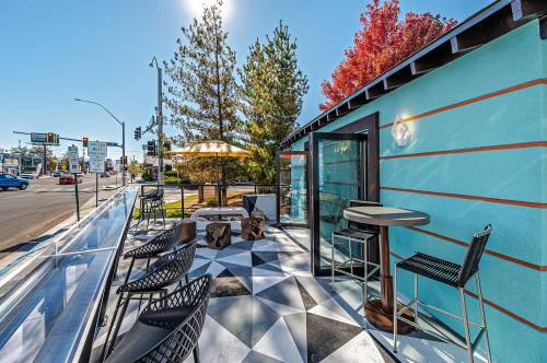 A vibrant outdoor seating area with modern furniture, surrounded by trees and a clear blue sky.