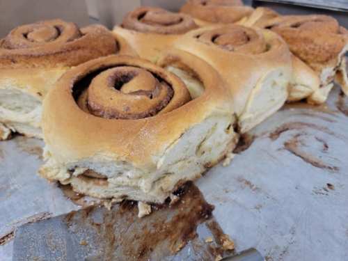 Freshly baked cinnamon rolls with swirls of cinnamon and sugar, resting on a metal tray.