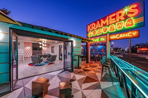 A vibrant retro motel entrance with colorful signage, outdoor seating, and modern decor at dusk.