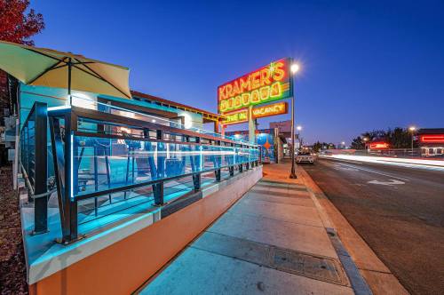 A brightly lit diner sign at dusk, with outdoor seating and a busy street in the background.