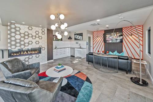 Modern living room featuring a geometric accent wall, stylish furniture, and a cozy fireplace. Bright and inviting space.
