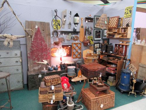 A vintage shop display featuring various antiques, including baskets, lamps, and decorative items on shelves.